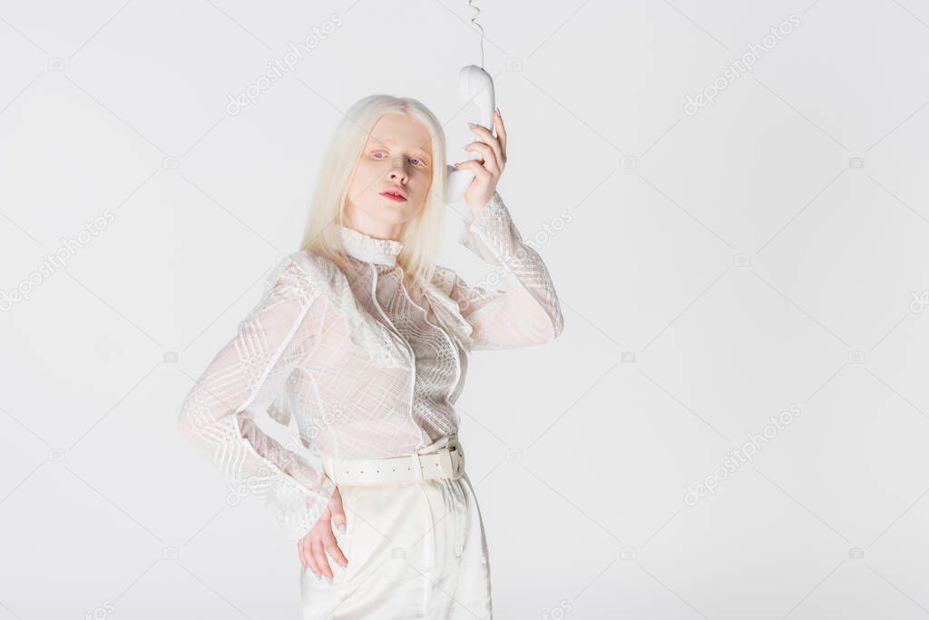 Stylish albino woman posing with telephone handset isolated on white
