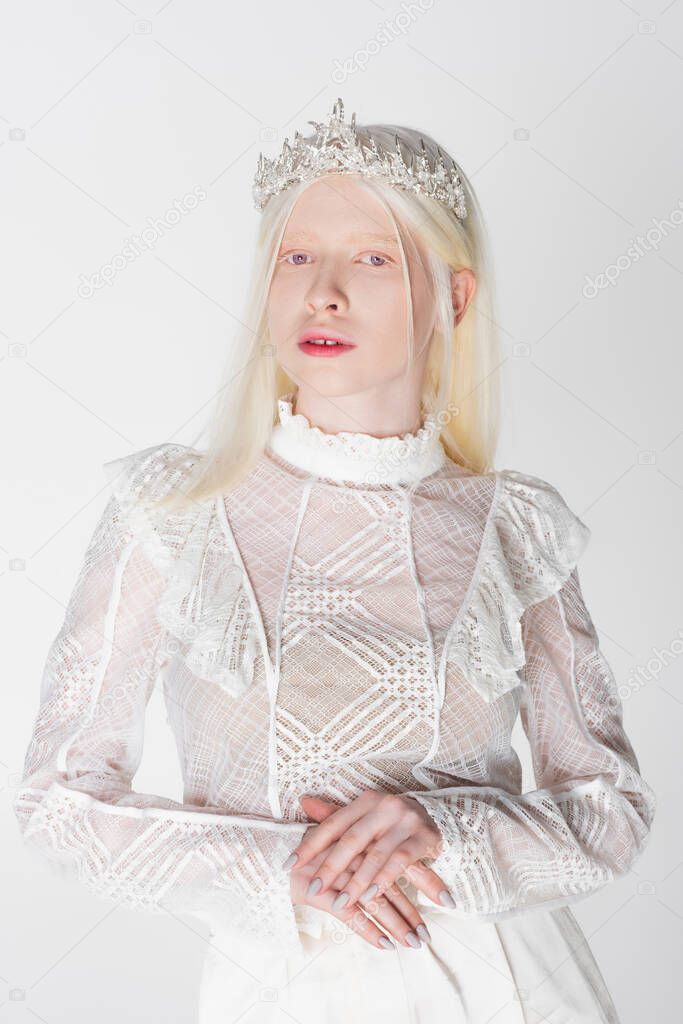 Young albino model in crown looking at camera isolated on white