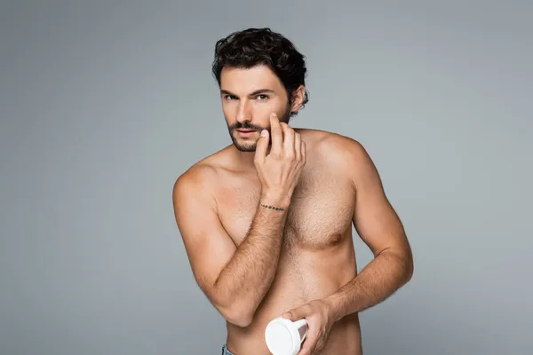 Hombre Tatuado Sin Camisa Sosteniendo Contenedor Aplicando Crema Cosmética Aislada — Foto de Stock