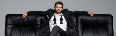 Siyah deri koltukta oturan sakallı adam. Gri pankartta izole edilmiş.