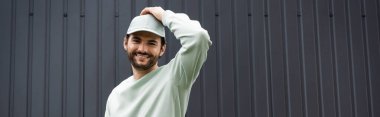 Tişörtlü gülümseyen adam metal çitlerin yanında kapak ayarlıyor.