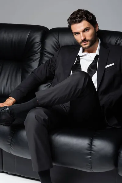 Tattooed Bearded Man Formal Wear Sitting Black Couch Isolated Grey — Stock Photo, Image
