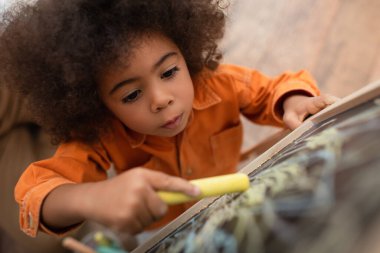 Afro-Amerikan çocuğun evdeki bulanık yazı tahtasına çizimlerinin en üst görüntüsü 