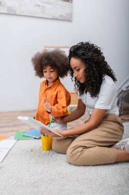 Afrika kökenli Amerikalı bir anne, elinde kitap ve evinde not defteri tutuyor. 