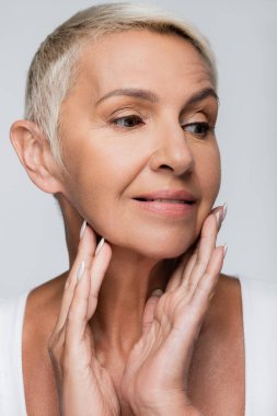 Neşeli, son sınıf öğrencisi bir kadın, bakışlarını kaçırıp, gri yüzlere dokunuyor.