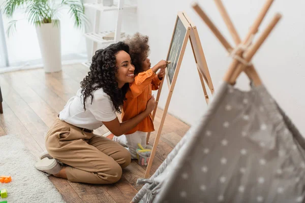 African American Parent Hugging Daughter Drawing Chalkboard Blurred Teepee Home — Stock Photo, Image