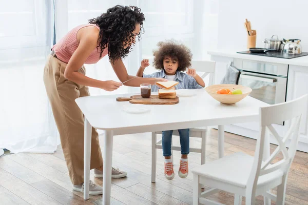 Africano Pai Americano Segurando Faca Pão Perto Filha Pasta Chocolate — Fotografia de Stock