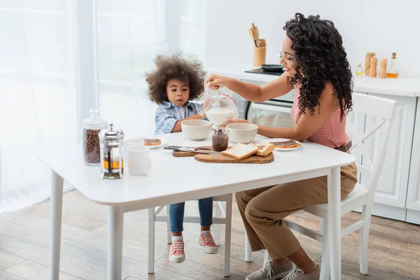 African American Mom Pouring Milk Breakfast Daughter Home — Stock Photo, Image