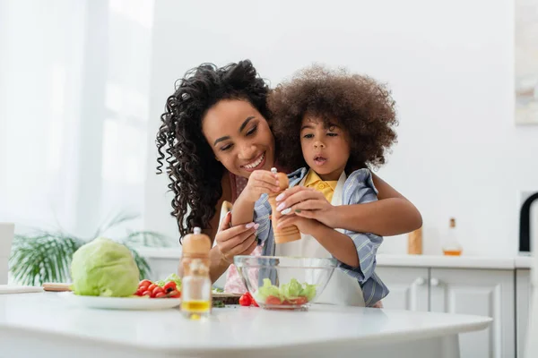 Smiling African American Mom Hugging Kid Pepper Mill Vegetables Home — Stock Photo, Image