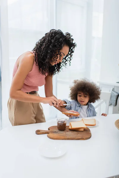 Donna Afroamericana Con Pane Coltello Vicino Alla Figlia Durante Colazione — Foto Stock