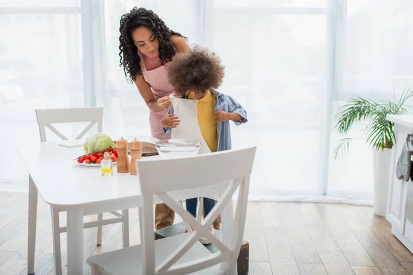 Femeie Afro Americană Poartă Șorț Fiică Lângă Legume Bucătărie — Fotografie, imagine de stoc