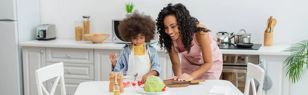 Niño Afroamericano Delantal Pie Cerca Mamá Verduras Frescas Cocina Pancarta — Foto de Stock