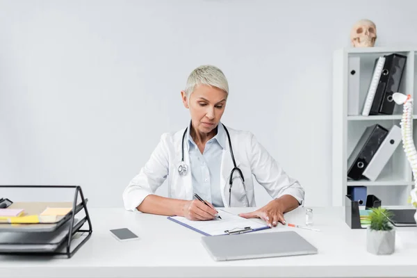 Médico Sênior Com Prescrição Escrita Cabelo Cinza Perto Dispositivos Mesa — Fotografia de Stock