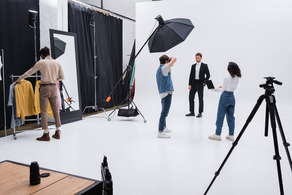 multiethnic team working during photo session with trendy model in studio