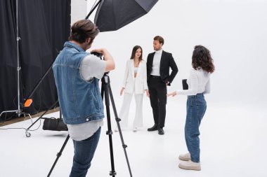 art director talking to models near photographer during photo session clipart
