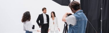 creative director talking to stylish models near photographer working in photo studio, banner clipart