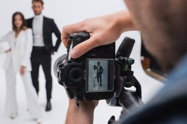 Fotoğraf makinesinin seçici odak noktası beyaz üzerinde bulanık modellerin yakınındaki fotoğrafçının ellerinde.