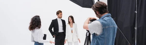 creative director talking to stylish models near photographer working in photo studio, banner