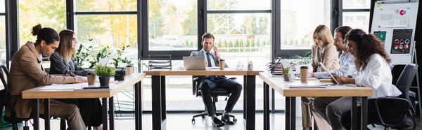 man in formal wear talking on mobile phone during business meeting with multicultural colleagues, banner