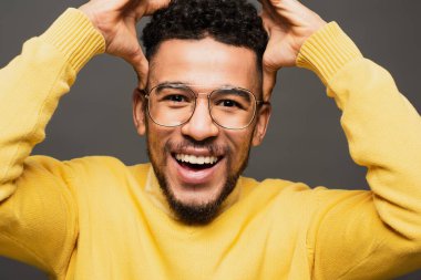 amazed african american man in glasses smiling isolated on grey clipart