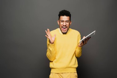Gözlüklü afro-amerikan adam elinde dijital tabletle koyu gri üzerinde