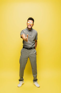 Güneş gözlüklü ve gri tenis tişörtlü Afro-Amerikan bir adam.