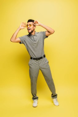 Gri tenis tişörtlü, sarı gözlüklü, neşeli Afro-Amerikan adam.