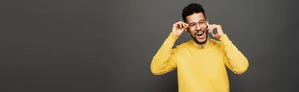 Χαρούμενος Αφροαμερικάνος Προσαρμόζοντας Γυαλιά Και Μιλώντας Στο Smartphone Σκούρο Γκρι — Φωτογραφία Αρχείου