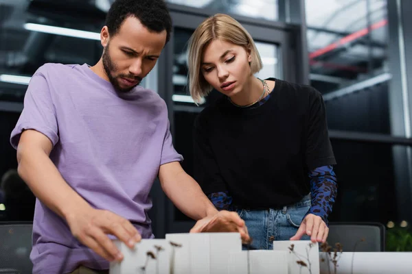 Bulanık ev modeline bakan çok ırklı genç mimarlar 