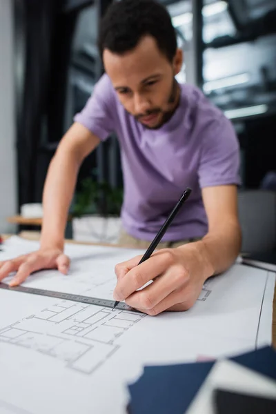 african american architect holding pencil and ruler near blueprint