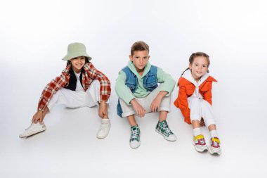 Beyazların üzerinde otururken gülümseyen şık çocuklarla dolu.