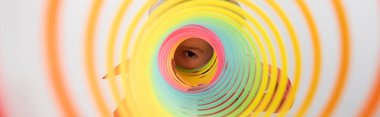 Çocuk bakıyor ve kamera gökkuşağından slinky beyaz pankartta