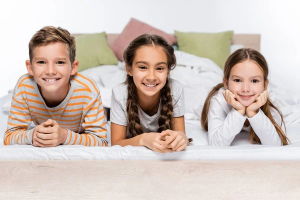 Niños Alegres Acostados Cama Sonriendo Aislados Blanco —  Fotos de Stock