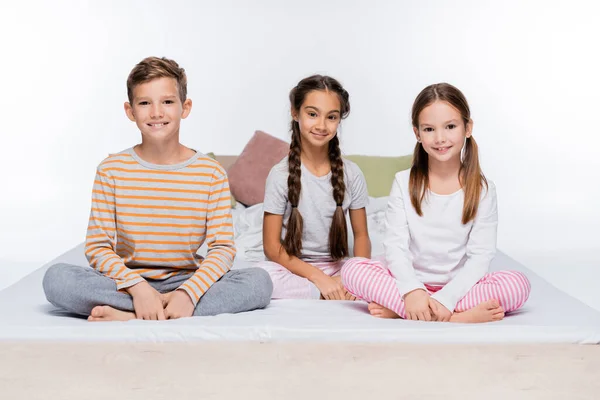 Niños Alegres Sentados Cama Sonriendo Aislados Blanco — Foto de Stock