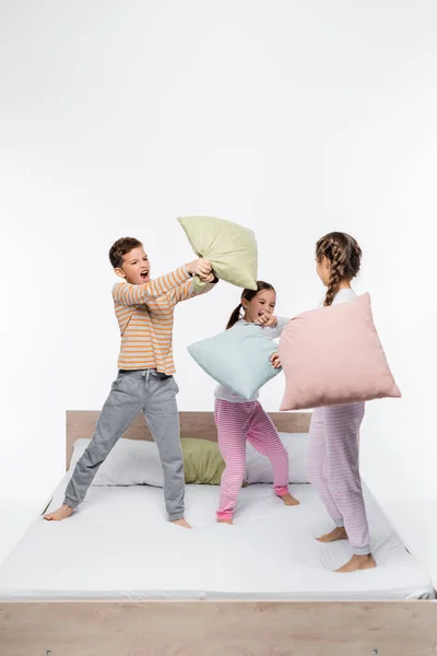 Zabawy Dzieci Piżamy Mając Walki Poduszki Stojąc Odizolowany Białym — Zdjęcie stockowe