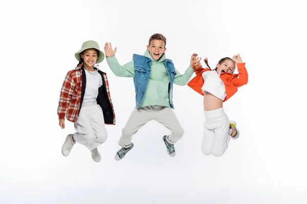 白いジャンプをしながら笑顔でいるスタイリッシュな子供たちの — ストック写真