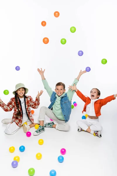 Веселые Детишки Сидят Бросают Разноцветные Мячи Воздух Белом — стоковое фото