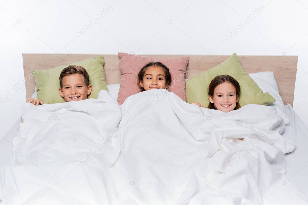 high angle view of happy kids lying under blanket isolated on white