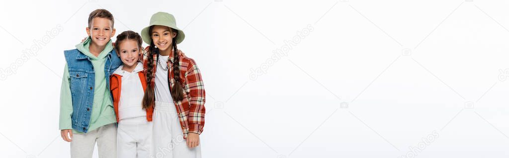 cheerful boy and stylish girls looking at camera isolated on white, banner
