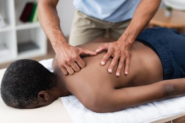 Rehabilitasyon uzmanı sırt masajı yaparken Afrikalı Amerikalıyı tedavi ediyor.