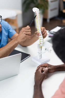 Rehabilitasyon merkezindeki bulanık Afrikalı Amerikalı bir adamın omurga modelini gösteren kısmi görüş.
