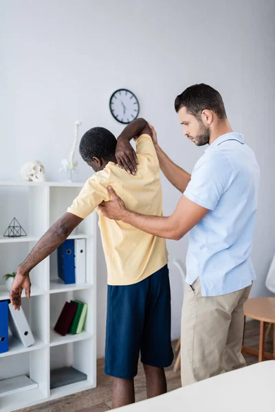 Joven Médico Tocando Paciente Afroamericano Mientras Diagnostica Centro Rehabilitación — Foto de Stock