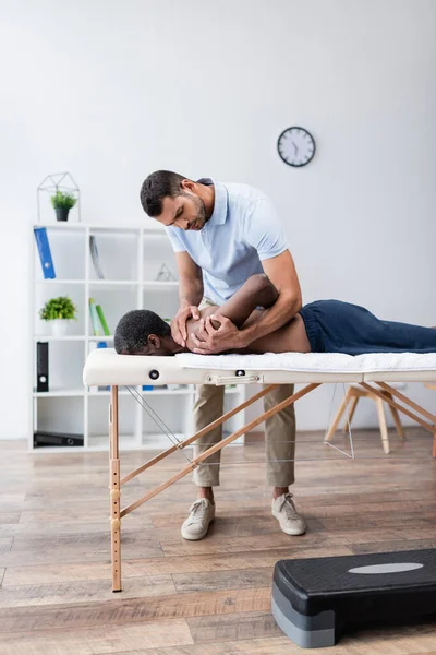 Fysiotherapeut Stretching Schouder Van Afro Amerikaanse Man Tijdens Revalidatie Procedure — Stockfoto