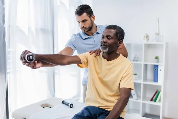 Mature African American Man Working Out Dumbbell Help Young Rehabilitologist — Fotografia de Stock