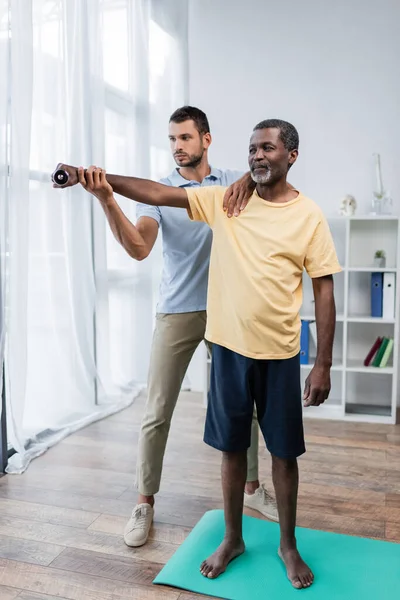 Full Length View Barefoot African American Man Exercising Dumbbell Rehabilitologist — 图库照片