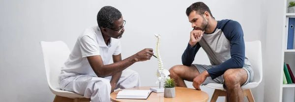 African American Rehabilitologist Pointing Spine Model Patient Consulting Room Banner — Fotografia de Stock