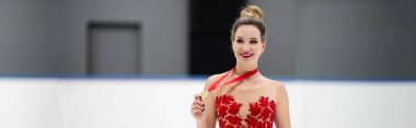 Kırmızı elbiseli mutlu artistik patinajcı elinde altın madalya, afiş