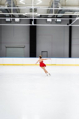 Donmuş buz arenasında artistik paten giyen genç bir kadın.