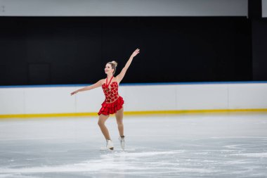 Profesyonel buz arenasında, madalyalı artistik patinaj yapan neşeli bir kadın.