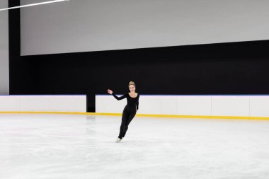 Profesyonel buz arenasında çalışan siyah elbiseli bir kadın.